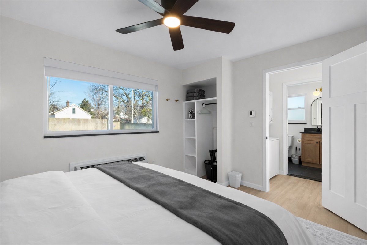 Spacious bedroom with a plush bed, ceiling fan, open storage, and direct access to the bathroom—designed for comfort, convenience, and a relaxing stay.