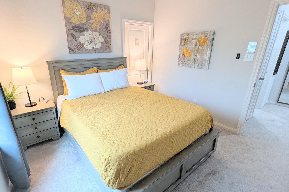 Bed has plush pillows and linens while bedside tables have easy access charging ports. 