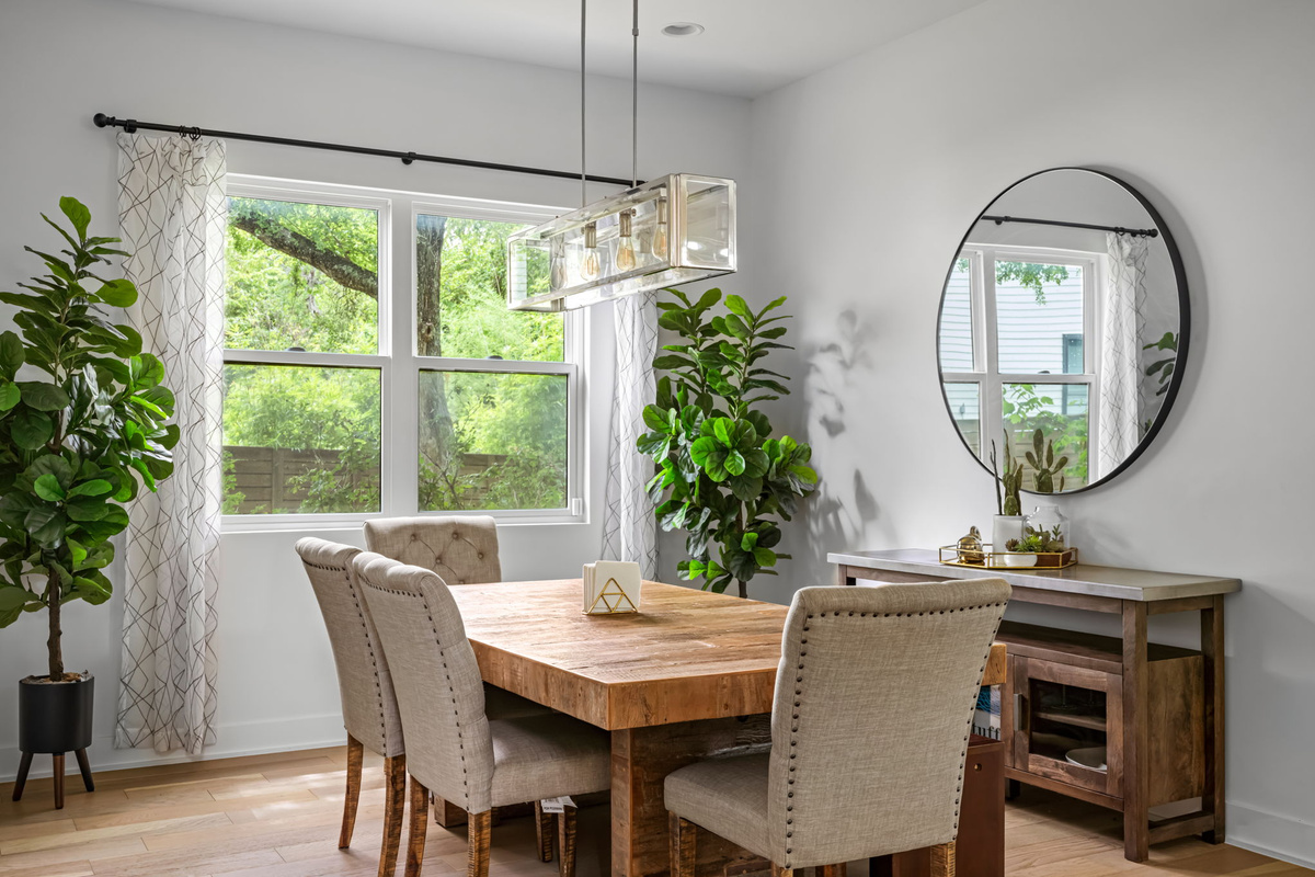Stylish dining room featuring a rustic wood table, round mirror accent, and chic sideboard — perfect for hosting family dinners.