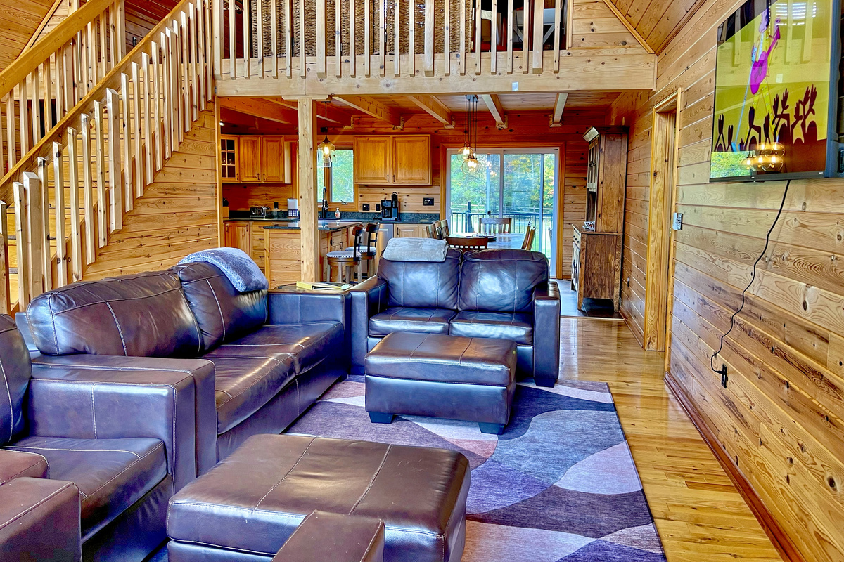 Stairs lead to a beautifully appointed loft bedroom, while the open-concept living area invites you to relax in comfortable leather seating and enjoy the 60-inch Smart TV.