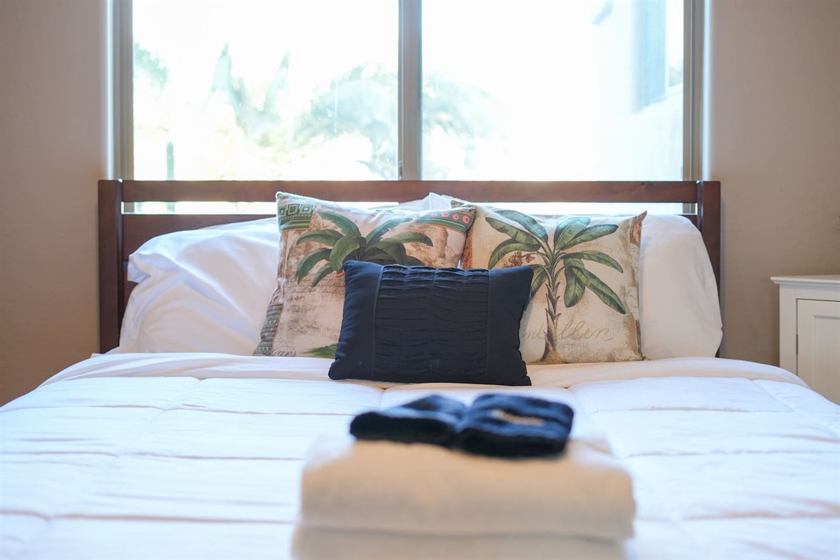 Queen bed with fresh linens and palm-inspired accents for a relaxing stay.