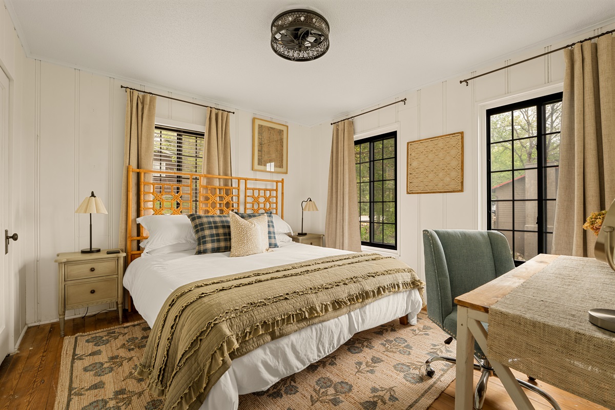 Primary bedroom with king bed and large windows.