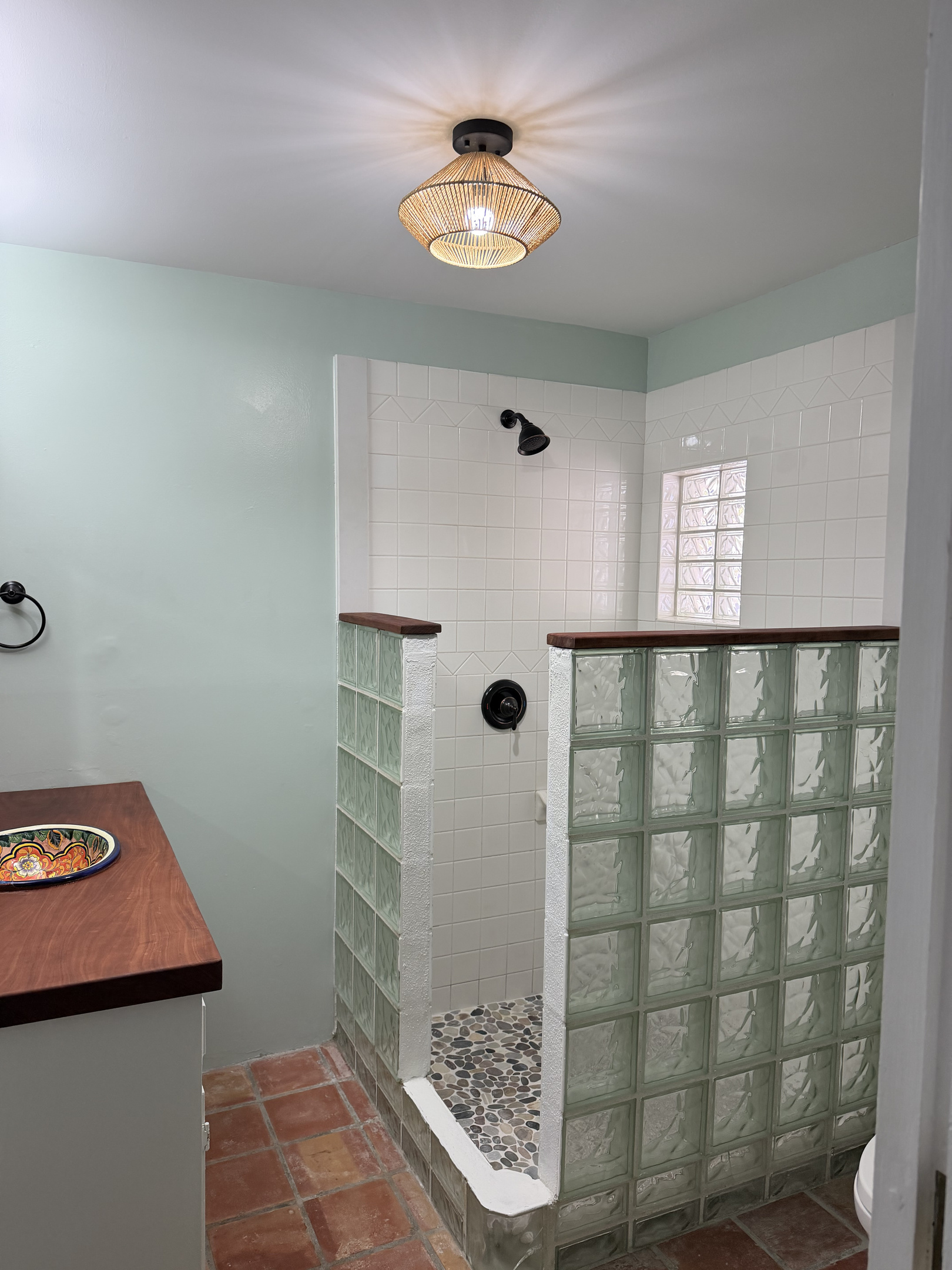 Primary bathroom offers spacious walk-in shower and is highlighted by a natural pebble floor and stylish glass-block walls that offer privacy while letting light filter through.