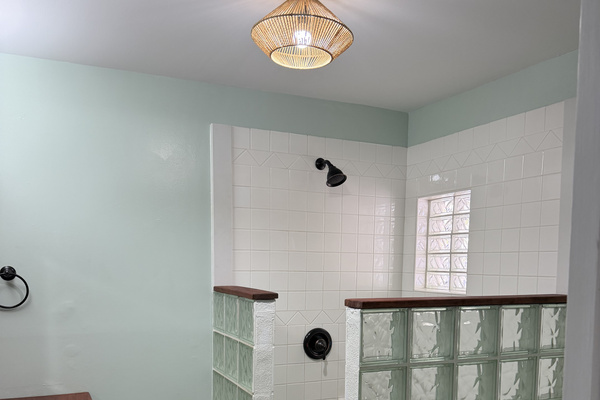 Primary bathroom offers spacious walk-in shower and is highlighted by a natural pebble floor and stylish glass-block walls that offer privacy while letting light filter through.