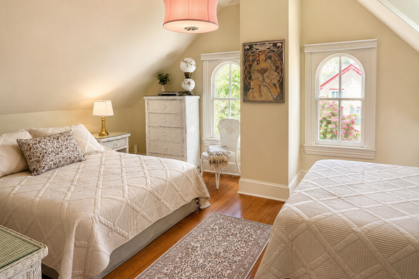Another angle of the same room — golden light, original hardwood floors, and enough space for everyone to be comfortable up under the eaves.