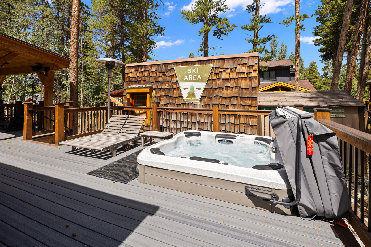 Outdoor living space with expansive deck, covered seating by bar-b-que grill (on far left), loungers, outdoor heating and in-ground hot tub. 