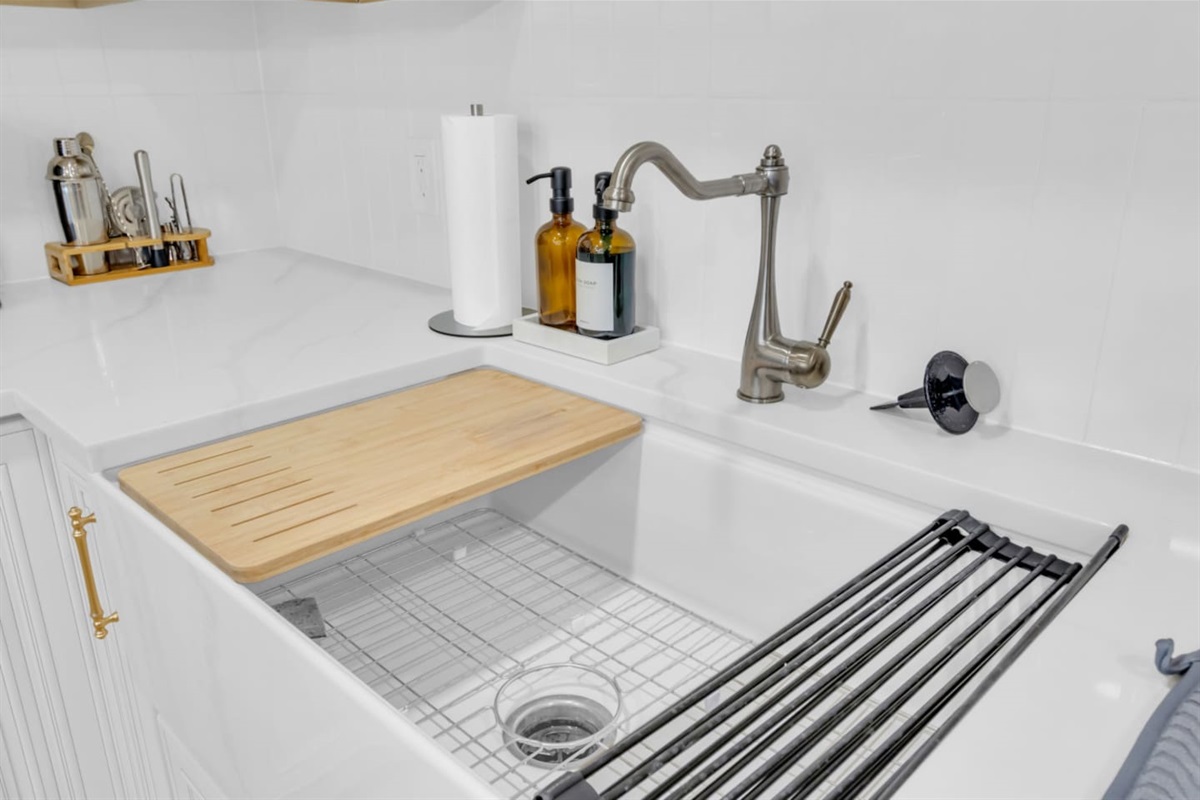 Sleek prep area with farmhouse sink, hand soap, dish soap, paper towels and stocked cleaning products. Designed for ease during long-term stays and everyday cooking.