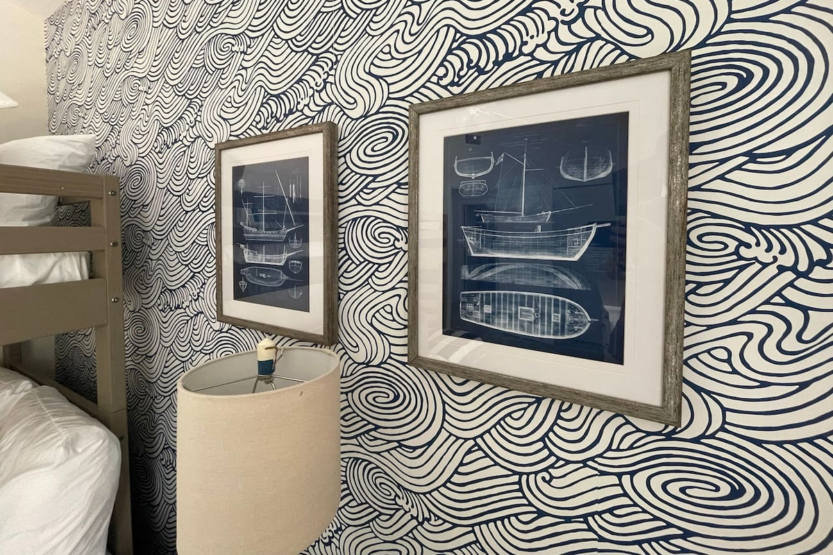 Waves swirl across the bunk room's wallpaper while framed ship blueprints chart the course — little sailors drift off to stories of the sea, then wake up ready for the real thing just a short walk from the front door.