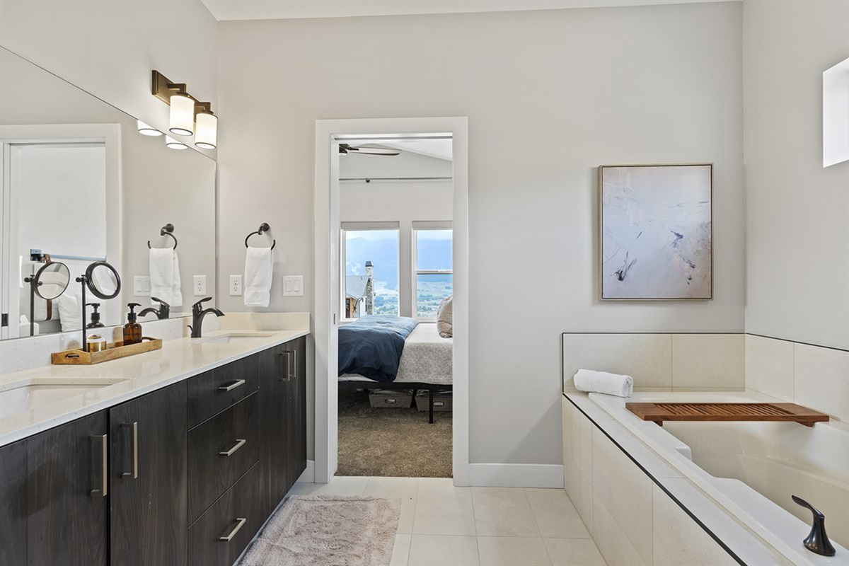 Spacious primary bathroom with soaking tub, dual vanity, and elegant finishes