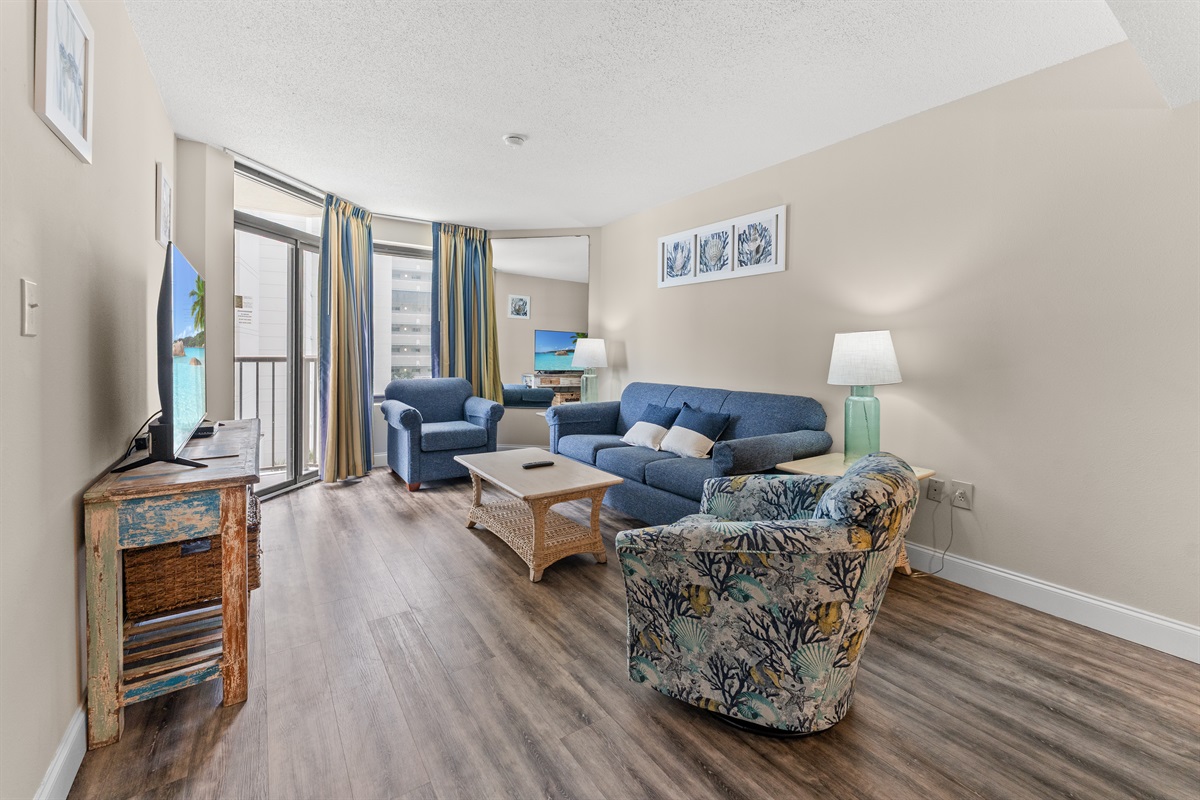 Large living room area with sleeper sofa, access to the balcony and large screen TV