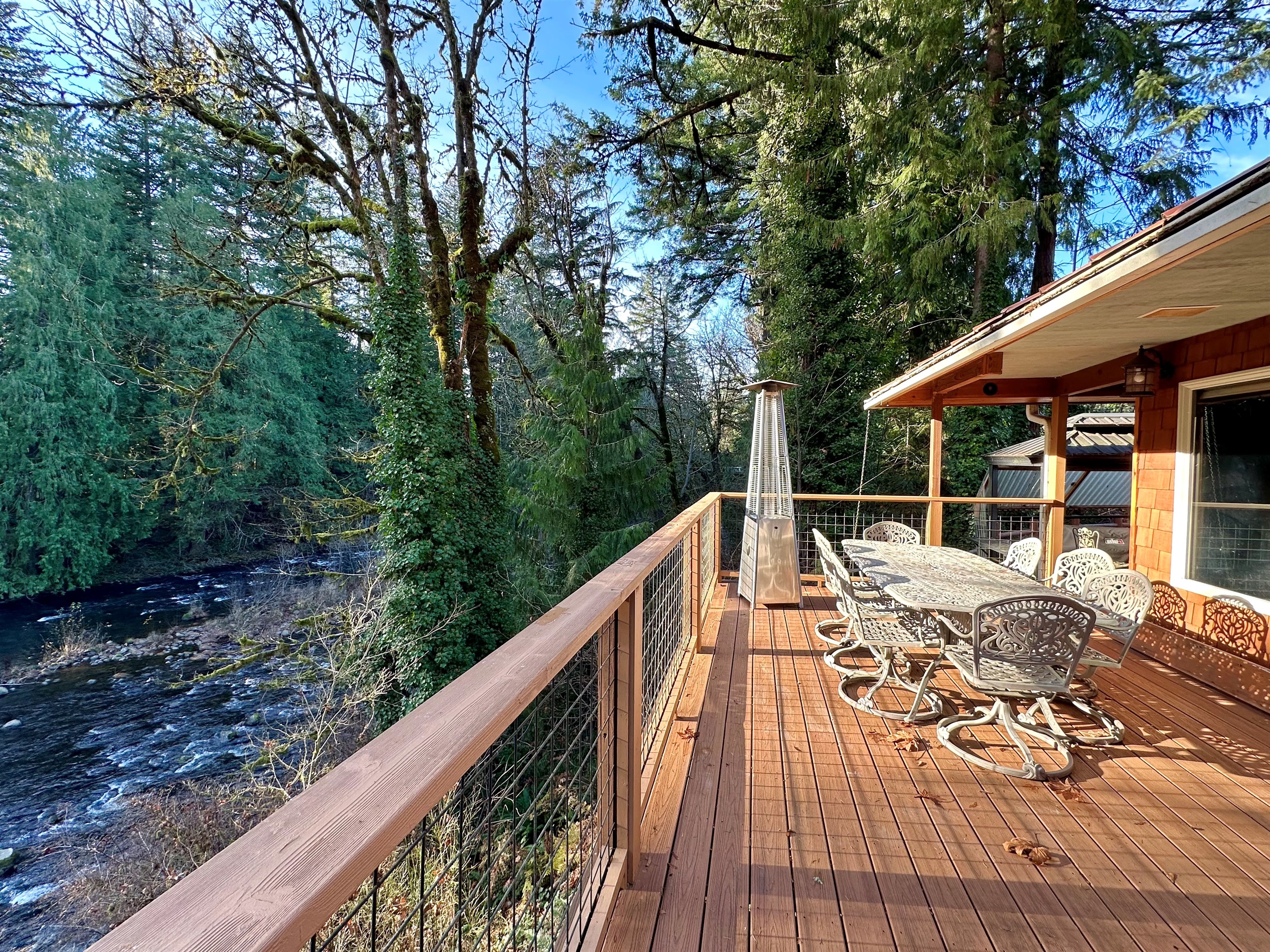 Soak up the sun and trees on 3 large decks overlooking the Salmon River from the main house. This deck is just off the living room and has plenty of room to eat outside on warm days.    