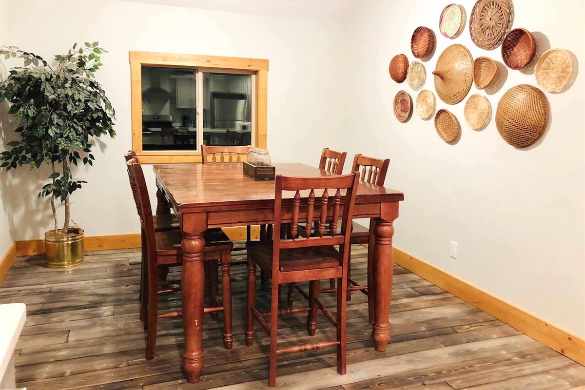 Unit B dining area with natural lighting, charming decor, and a table that makes a great gathering spot for mealtimes and game nights.
