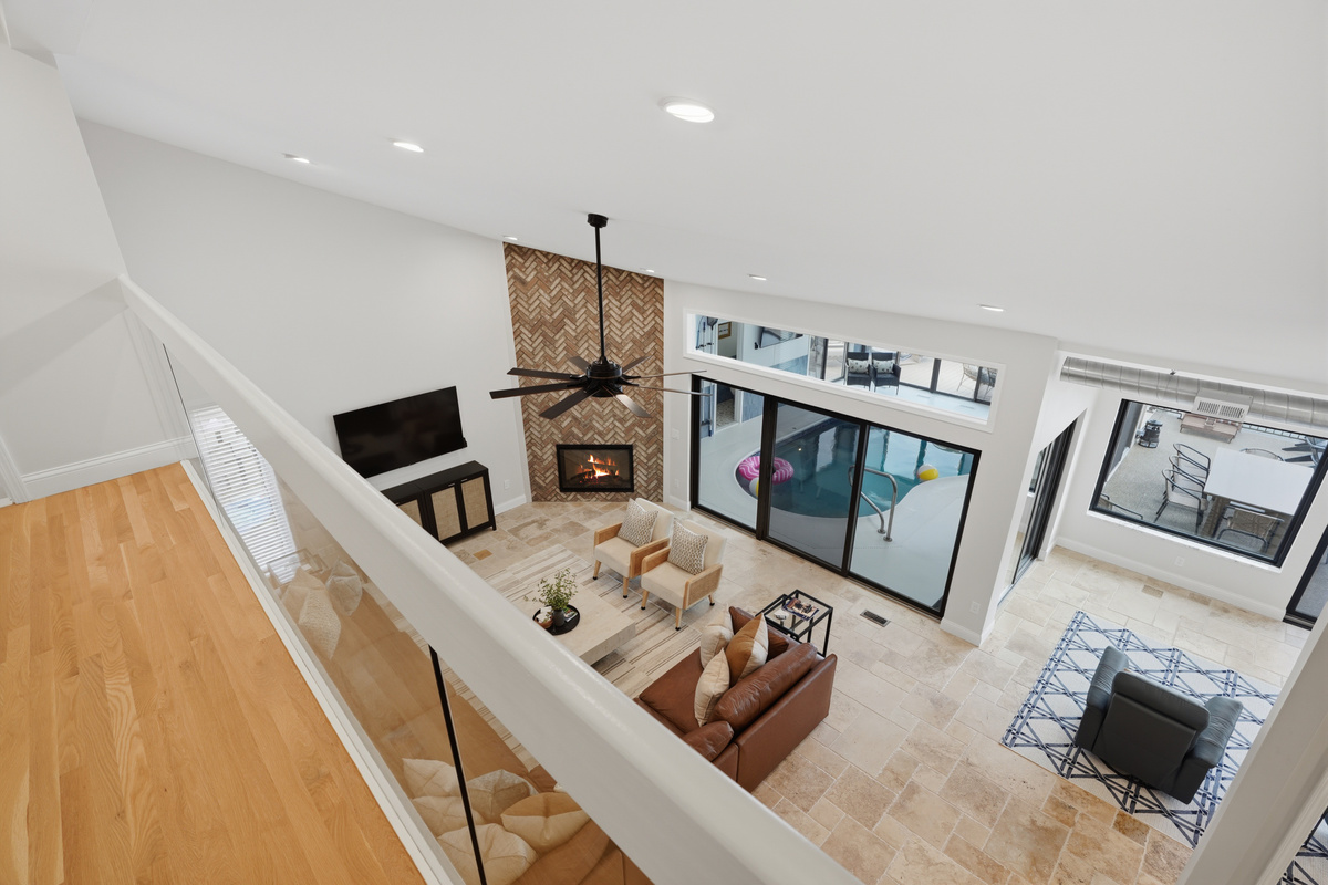 Bright, open-concept living space with high ceilings, fireplace, and large windows creating a light and airy feel perfect for relaxing or entertaining.