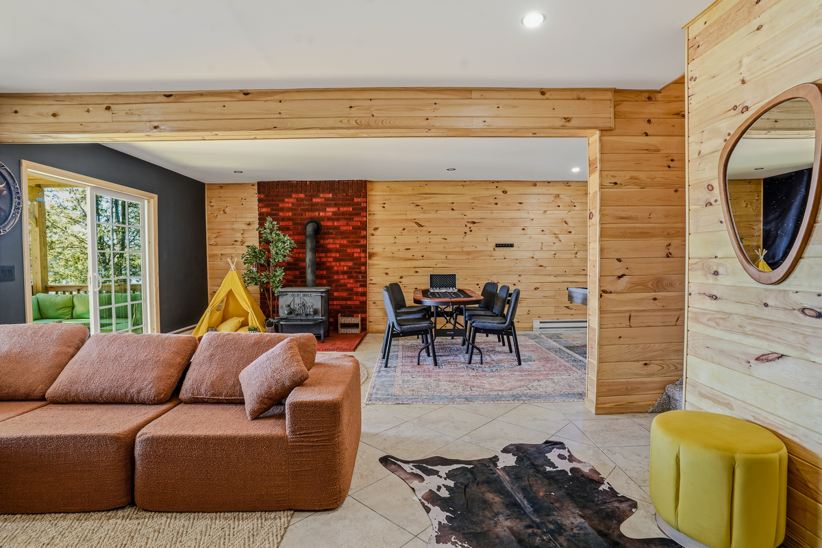 Lower-level living room with leather sectional, wood stove, cowhide rug, and lake access