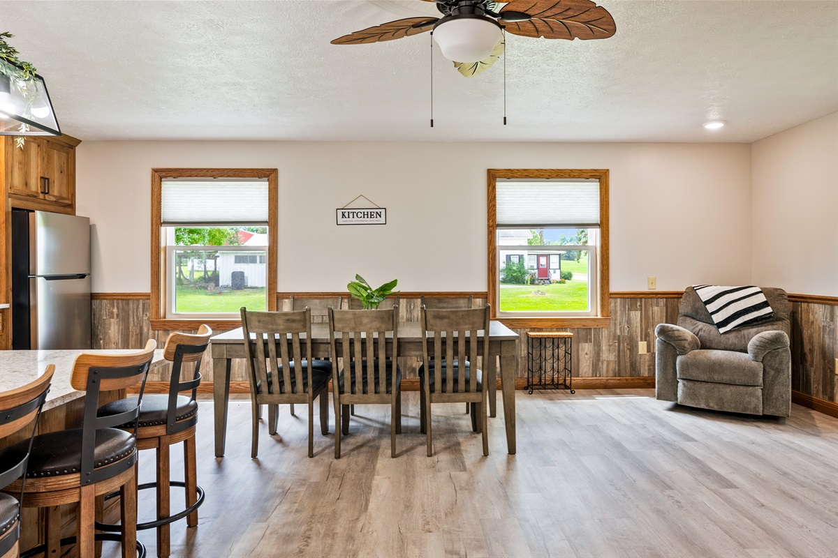 Enjoy meals with a view in this bright dining area featuring large windows, rustic wood accents, and cozy seating for six.