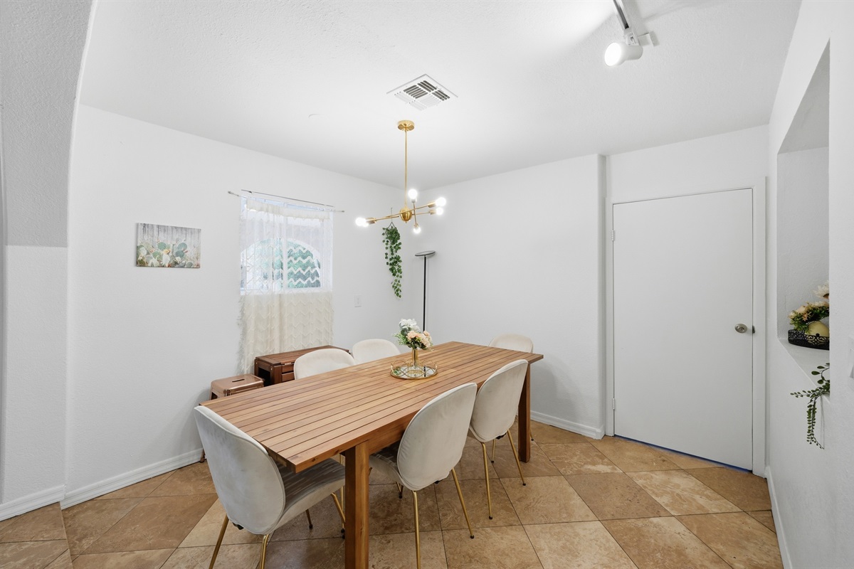 Gather for meals or game nights in this stylish dining room, featuring warm textured walls, modern lighting, and a cozy, intimate atmosphere.