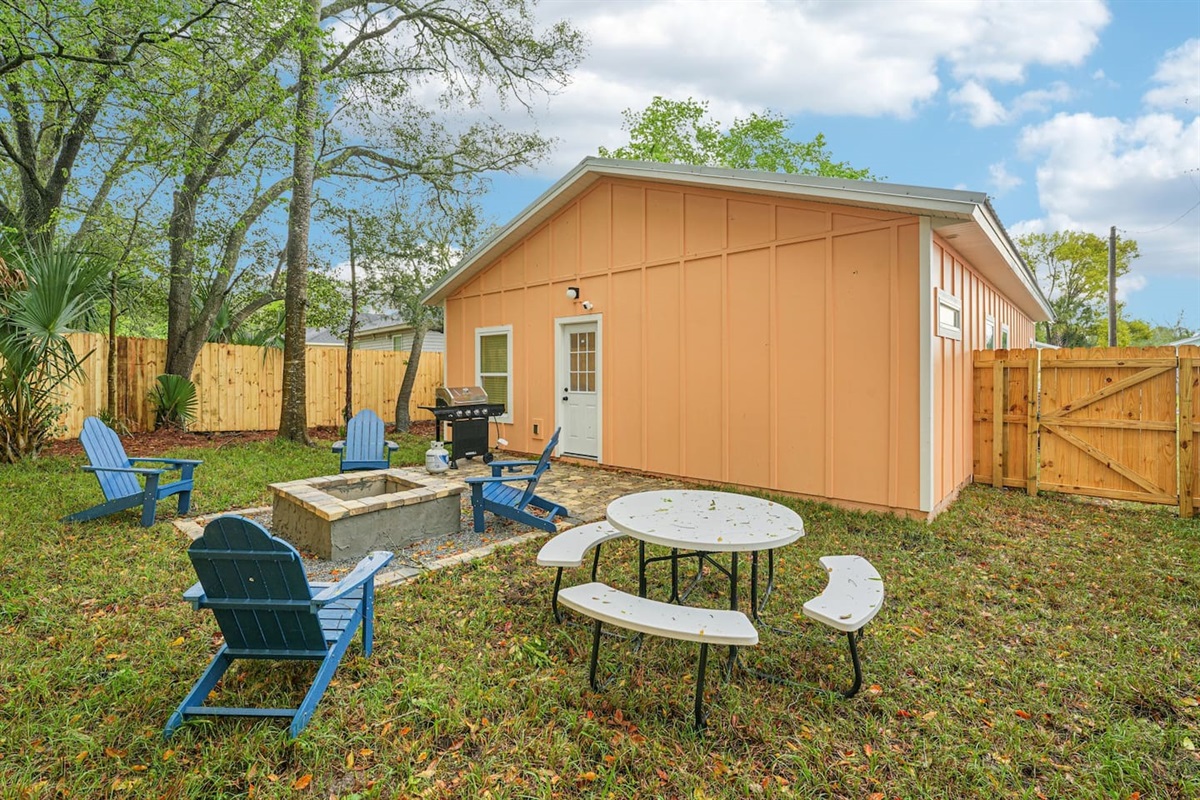 Outdoor area has a stone patio, stone fire pit, 4 adirondak-style chairs, and an 8-seat picnic table, with a fully fenced, private backyard.