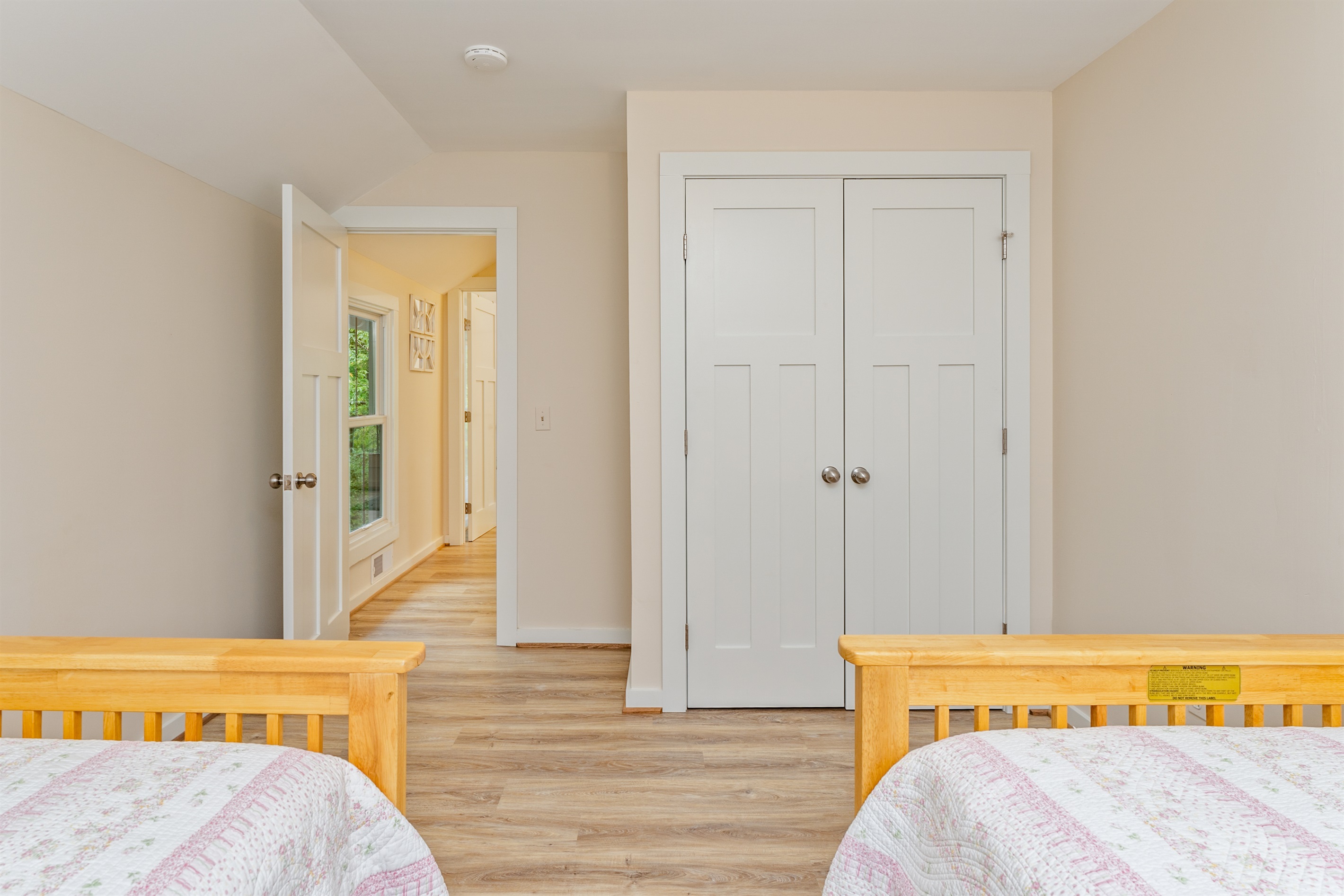 Bright and cozy bedroom with twin beds, a spacious closet, and warm wood accents—perfect for kids or extra guests.