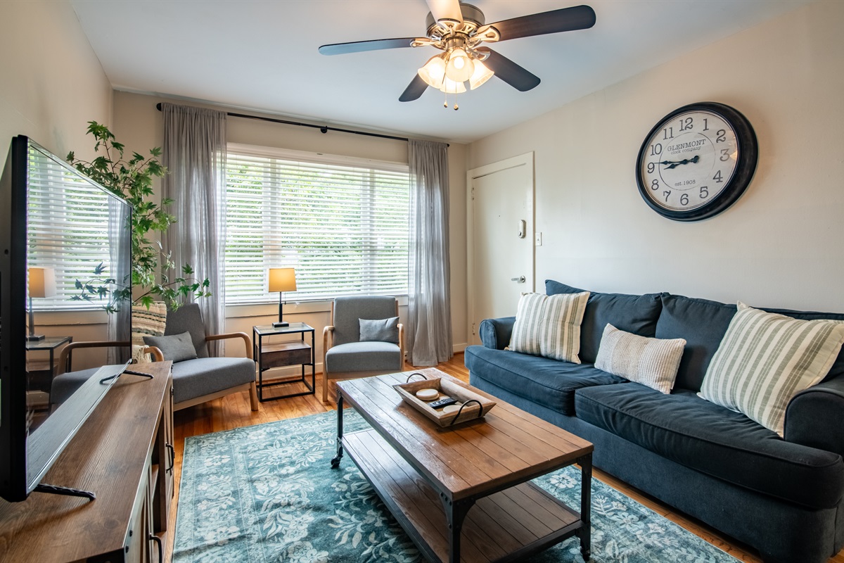 Bright and cozy living room featuring a comfy sofa, wall clock, and beautiful natural light.