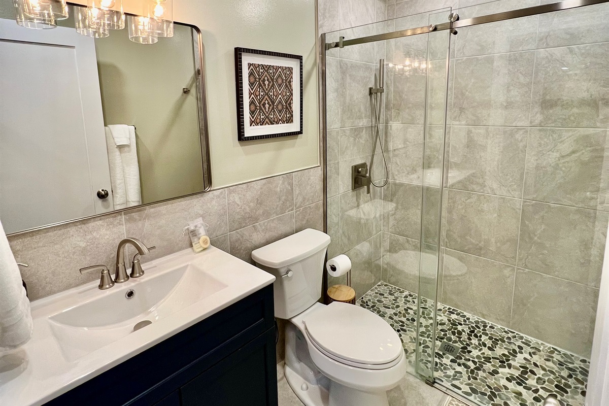 Refresh in the sparkling clean, modern bathroom, featuring a walk-in shower with a river rock floor and a relaxing rainfall showerhead.