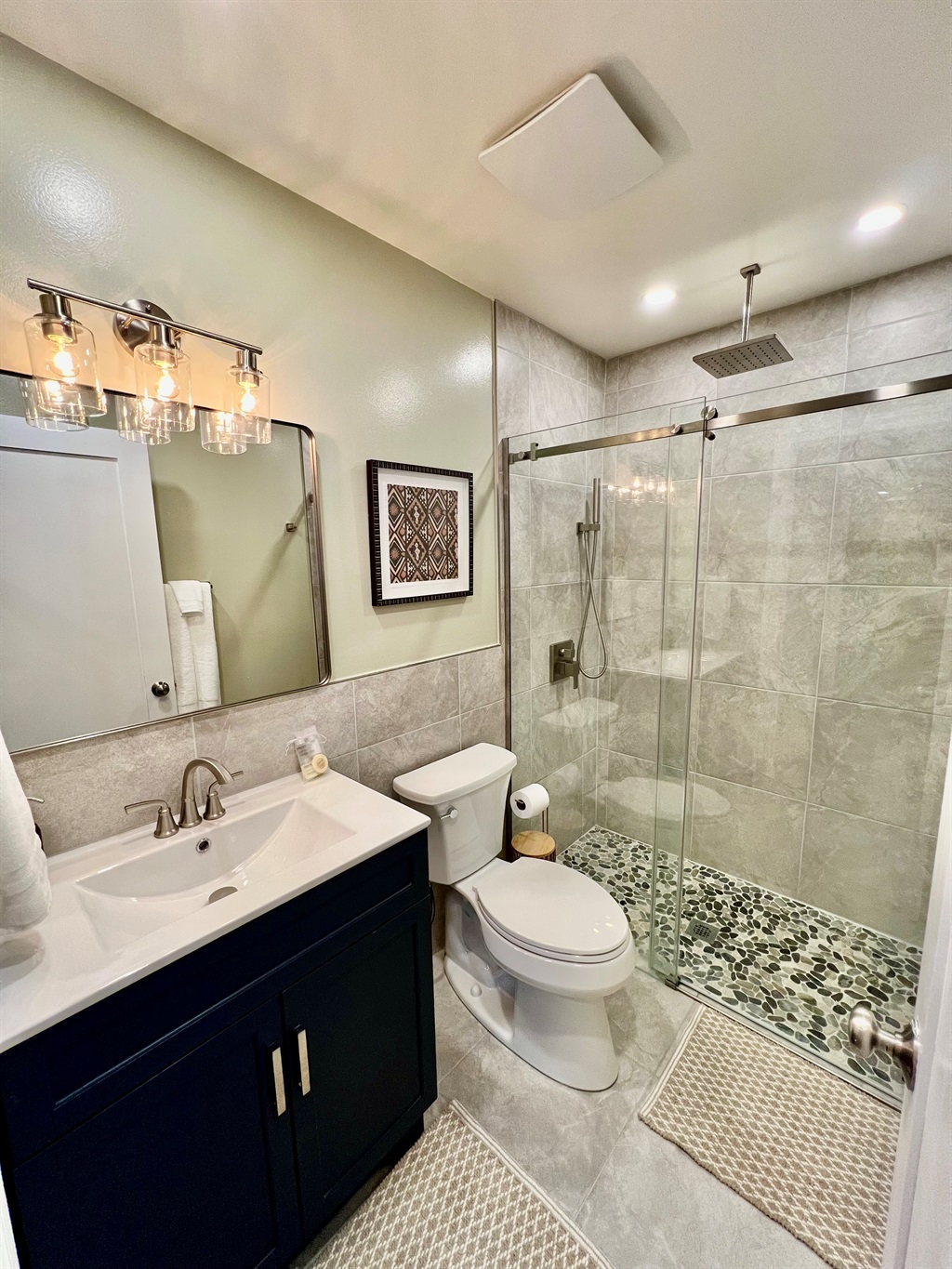 Refresh in the sparkling clean, modern bathroom, featuring a walk-in shower with a river rock floor and a relaxing rainfall showerhead.