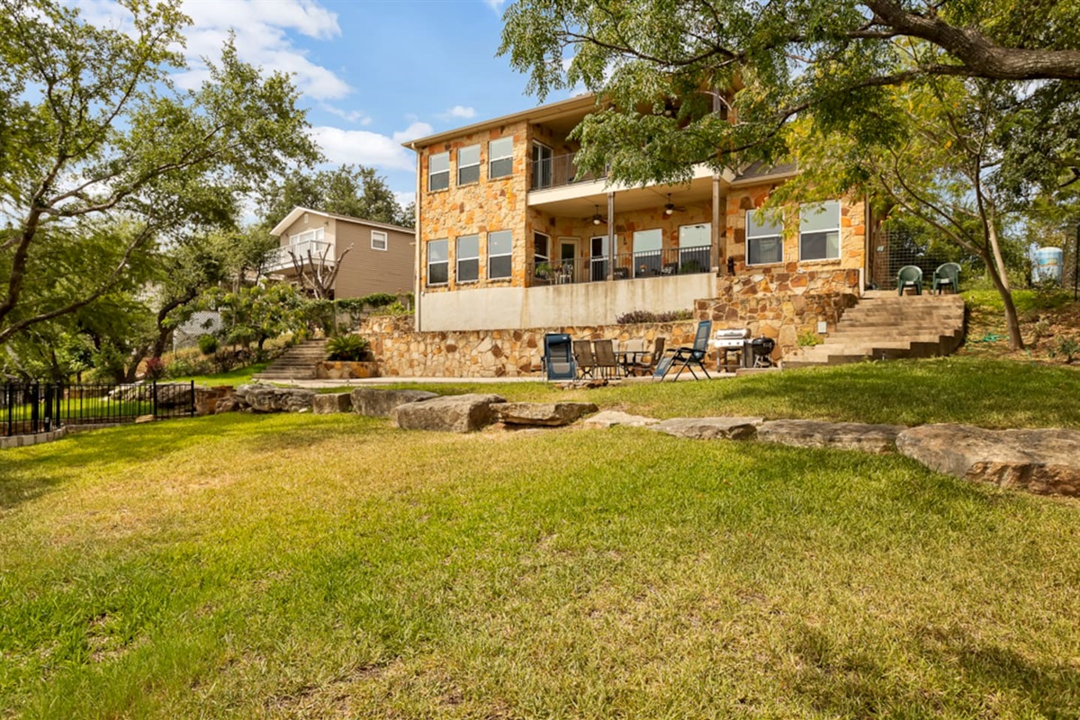 Back of home with large yard, fire pit and grilling areas