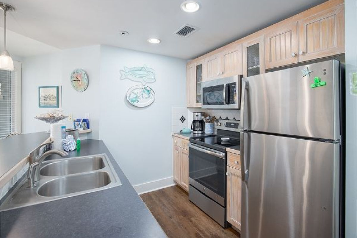 Full kitchen with stainless refrigerator, range and microwave, double sink and whitewashed cabinets