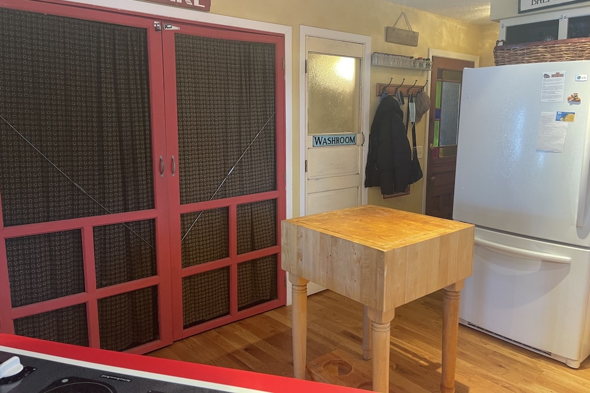 Washer and Dryer behind red screen doors with bathroom next to it