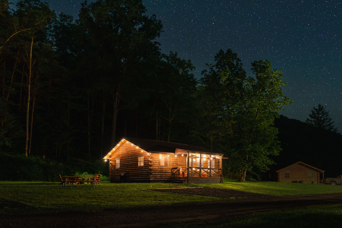 🌌 Cabin #3 glowing in the woods at dusk — Denton Hill at its best