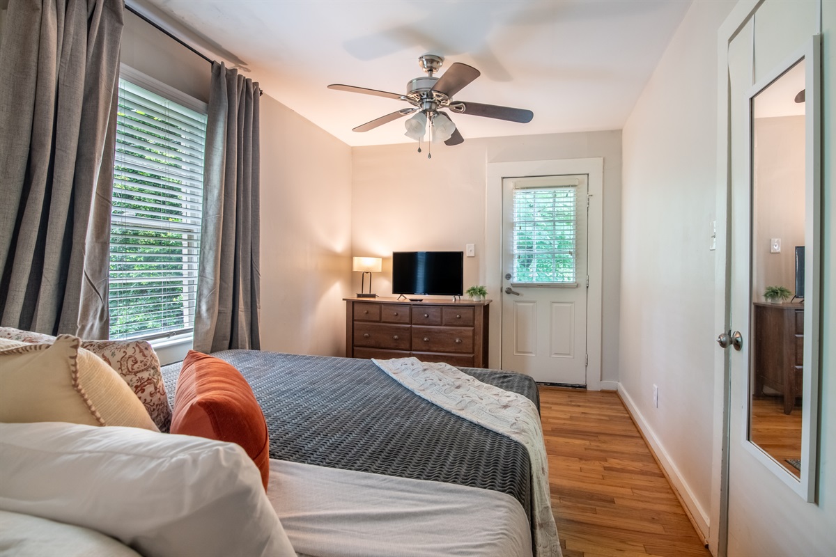 Spacious bedroom with a king bed, ceiling fan, and access to a private workspace.