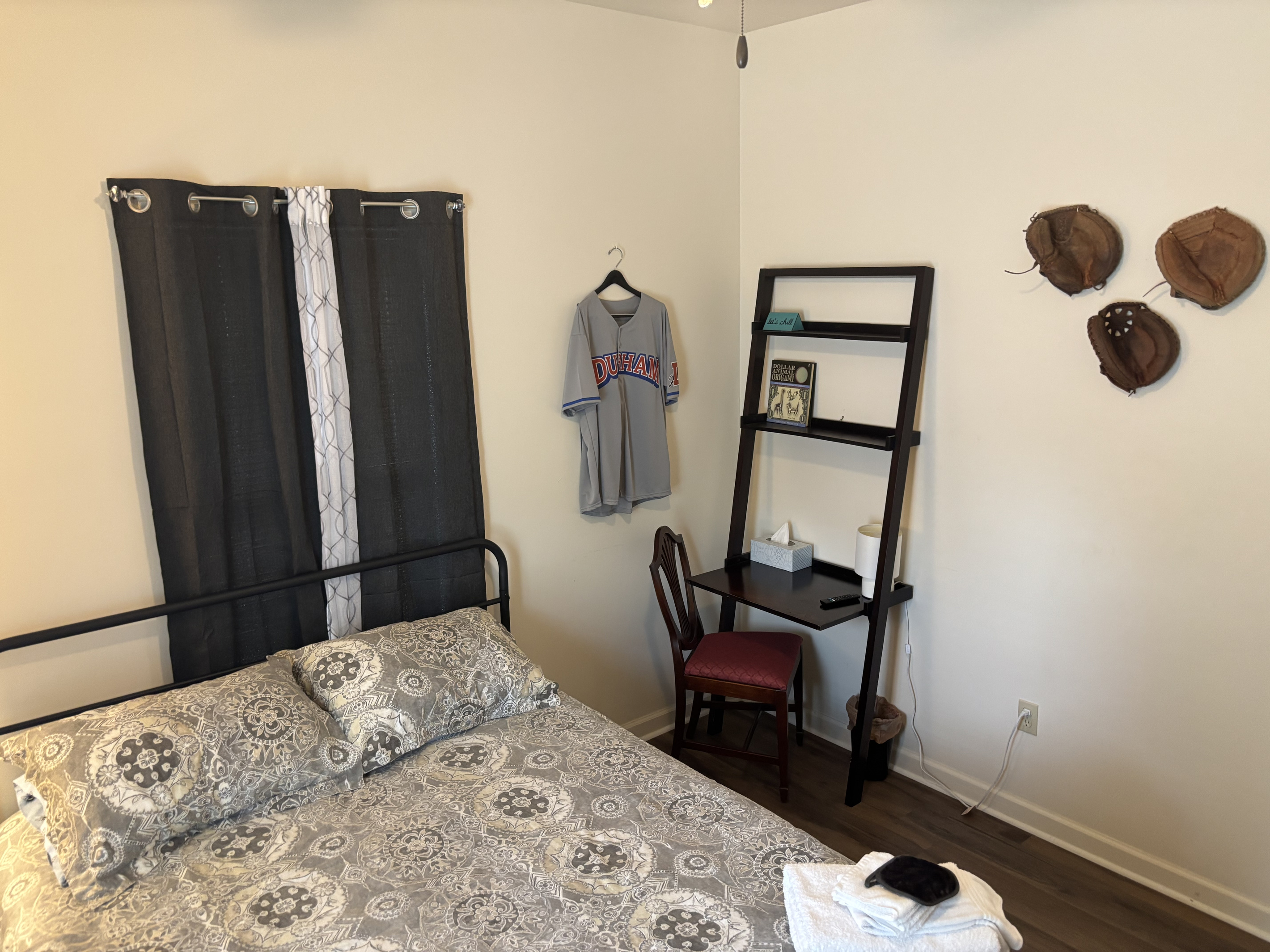 The queen bedroom includes a compact laptop desk and vintage Durham Bulls touches.