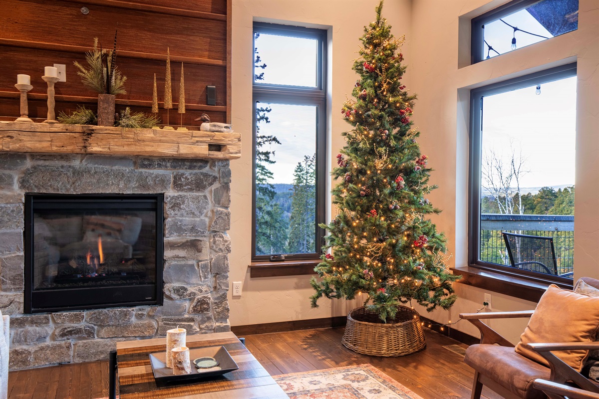 Cozy holiday corner at Lost Camp Lodge—warm up by the stone fireplace and enjoy mountain views beside the beautifully lit Christmas tree. A perfect spot for quiet mornings, gifts, and gathering with family.
