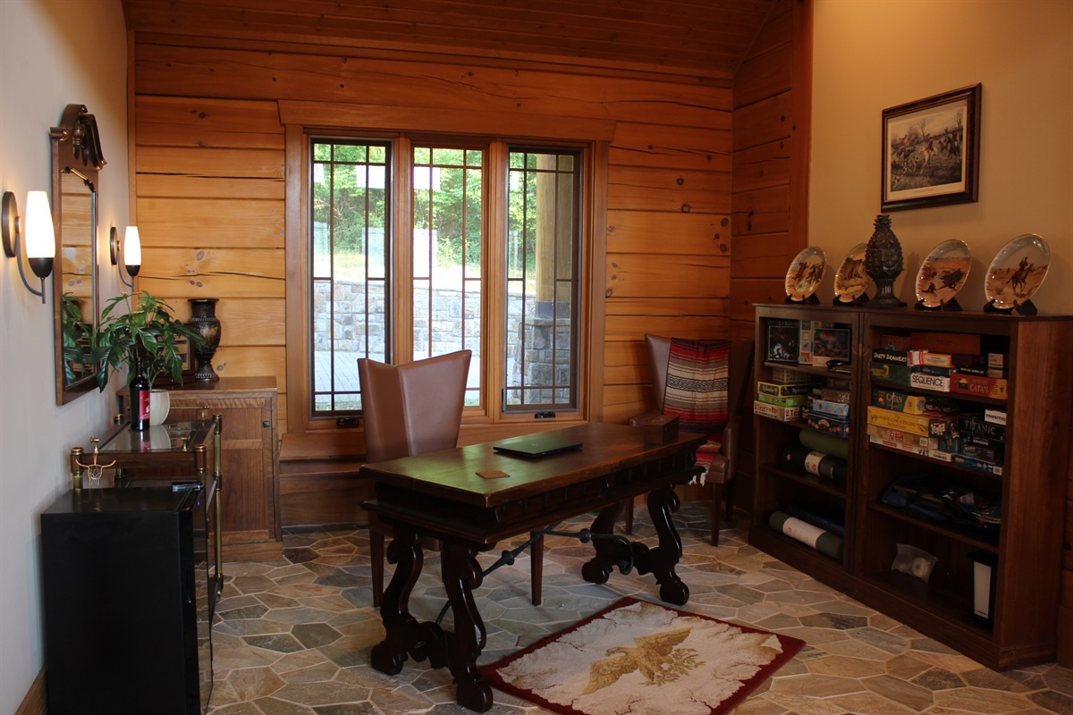 A versatile office space featuring a desk and shelves stocked with games, perfect for remote work or family fun.