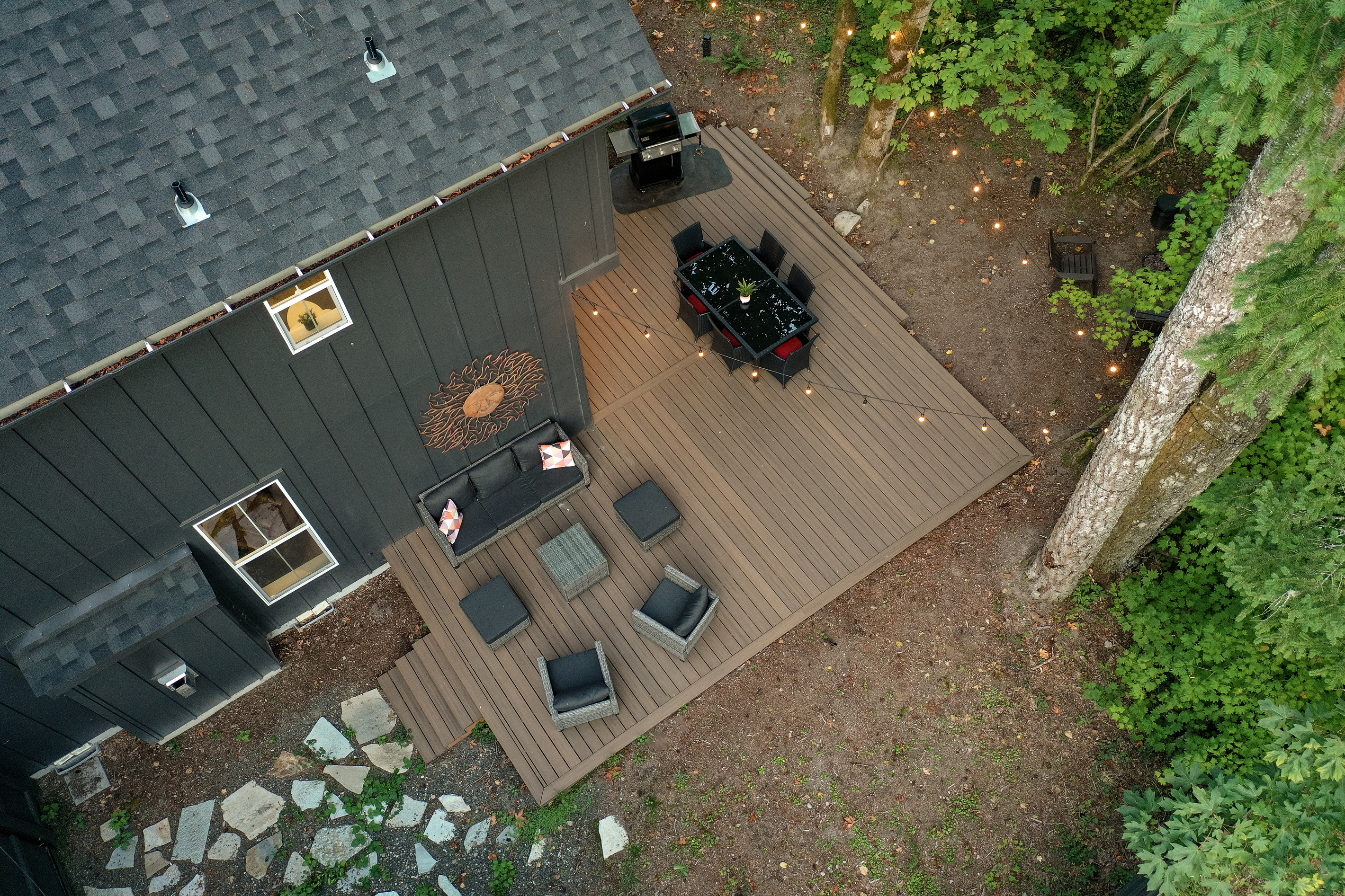 Dinner under the string lights: an aerial look at the deck, dining table, and grill tucked into the Mt. Hood forest.