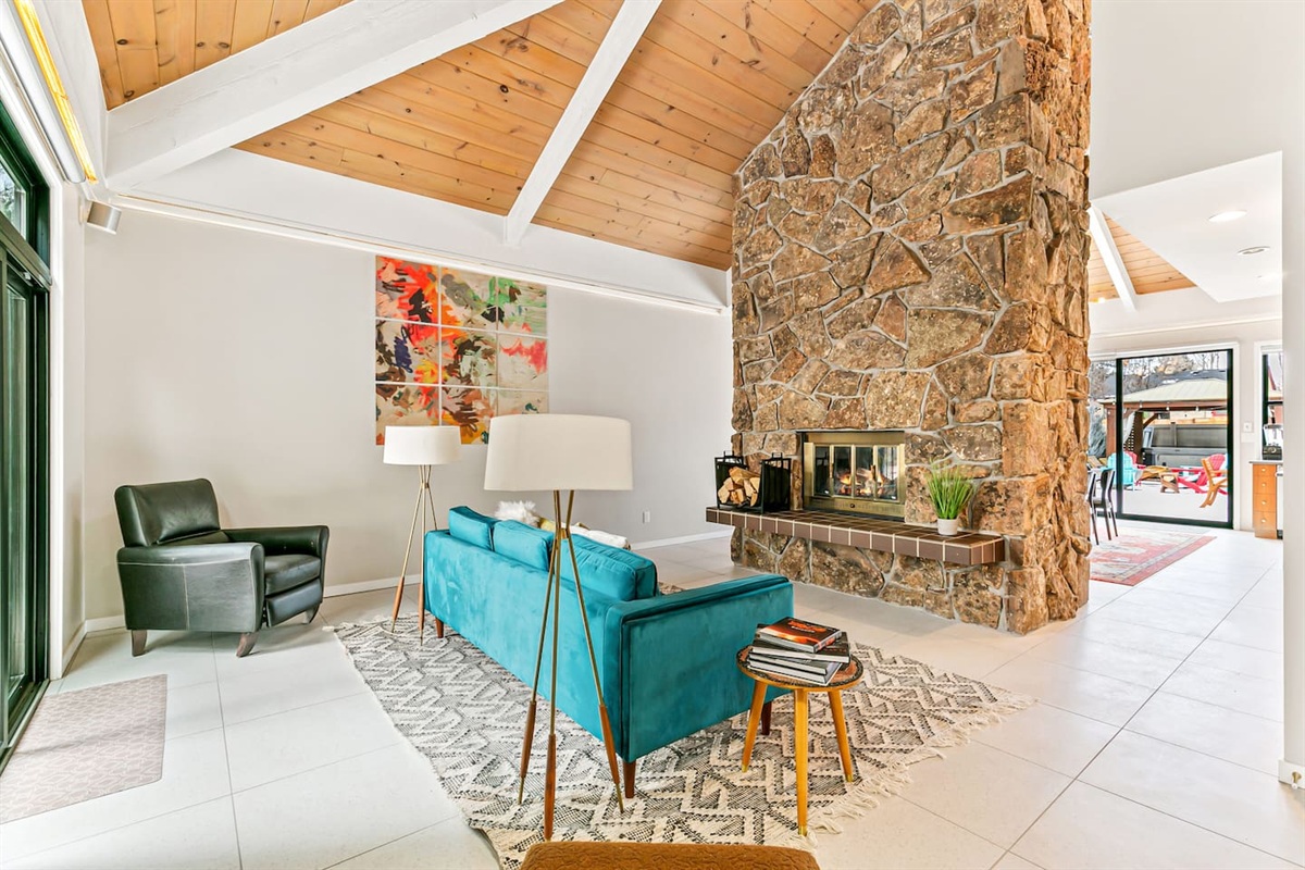 Welcome to the enchanting Living Room, furnished with a velvet sofa for intimate conversations, a two-sided fireplace, and easy access to the outdoor area, kitchen, and patio.