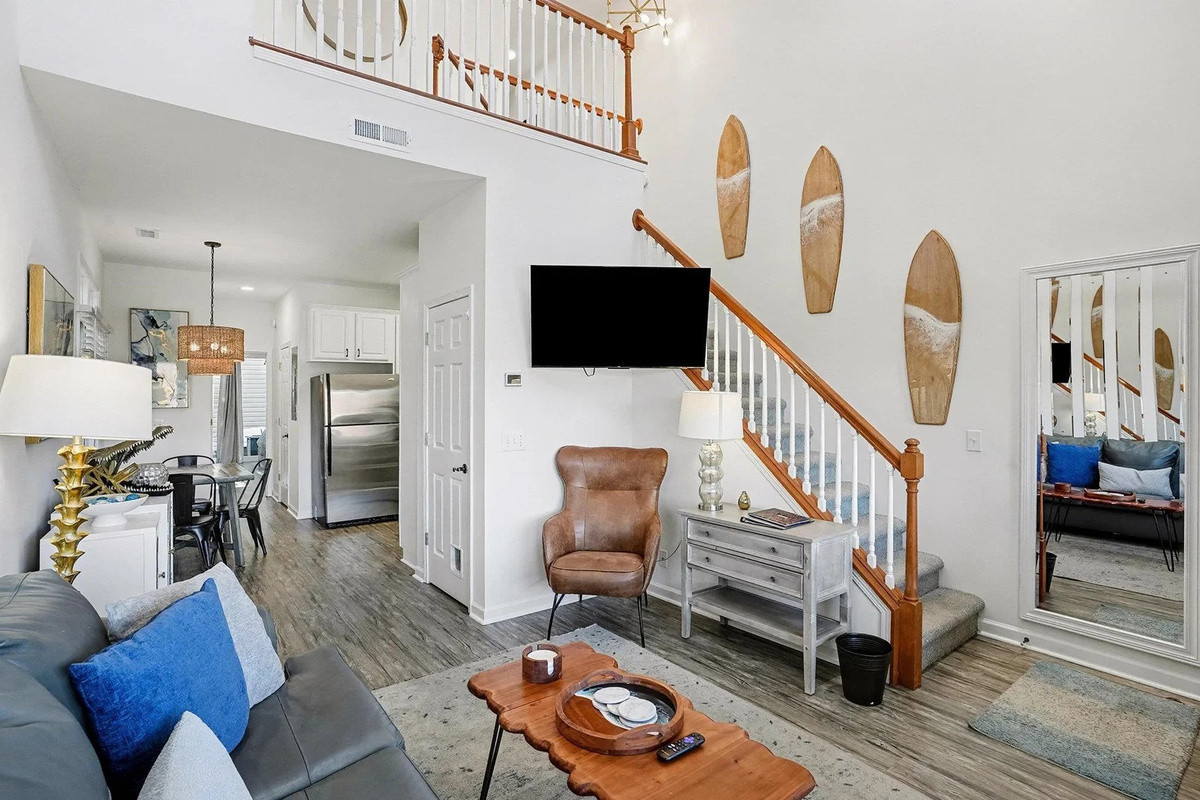 Vaulted living room with surfboard wall, smart TV, and light-filled bay windows