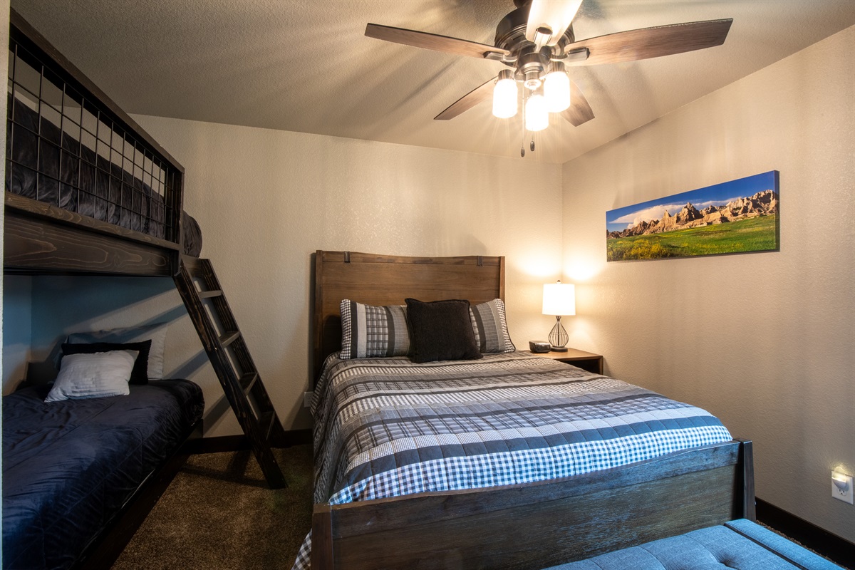 A perfect family setup—this spacious main floor room features a cozy queen bed and twin bunks, making it ideal for parents and kiddos to stay close and comfortable.