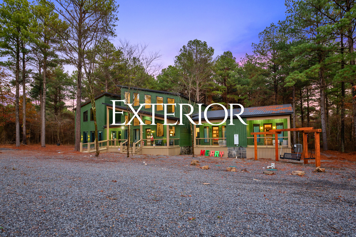 The home&rsquo;s exterior glows warmly at sunset, blending seamlessly with the surrounding woods for a picturesque scene.