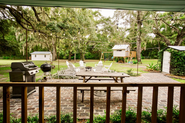 The view from the back French doors - brick patio grills, and string lights under the oaks.