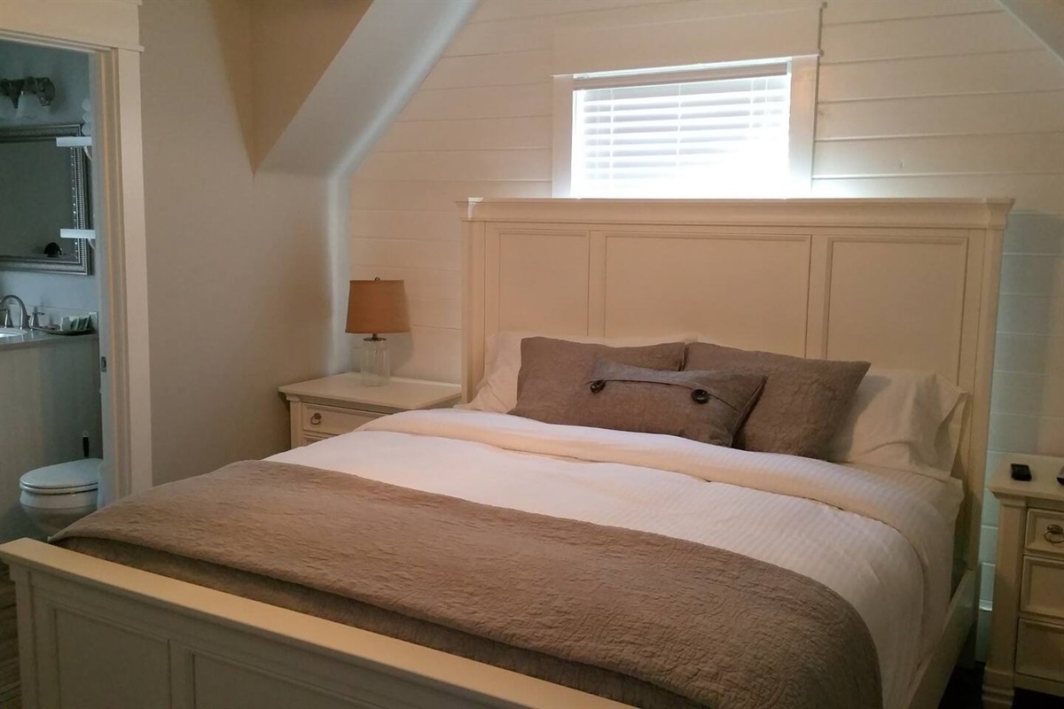 king size bed in upstairs bedroom of white cottage rental in Mena, Arkasas