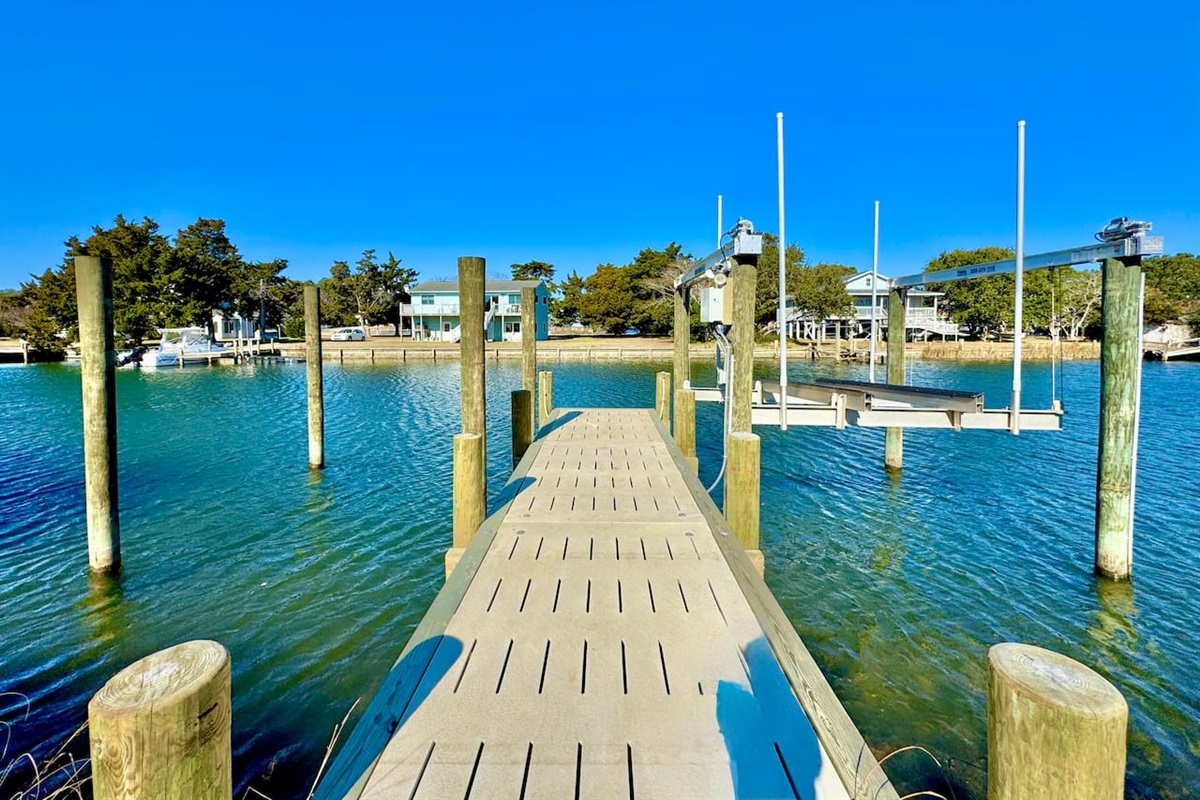 Private backyard dock with boat lift and fillet table, fenced-in backyard, fire pit with Adirondack chairs, hammocks, propane grill, picnic table, outdoor shower, expansive waterfront back deck, neighborhood boat ramp and dock