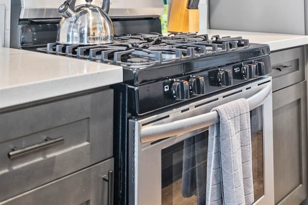 Cook and connect in our spacious kitchen, featuring a stylish sink, oven, and coffee maker. The open floor plan offers a delightful view of the cozy dining table and living room, making it an ideal space for family gatherings.