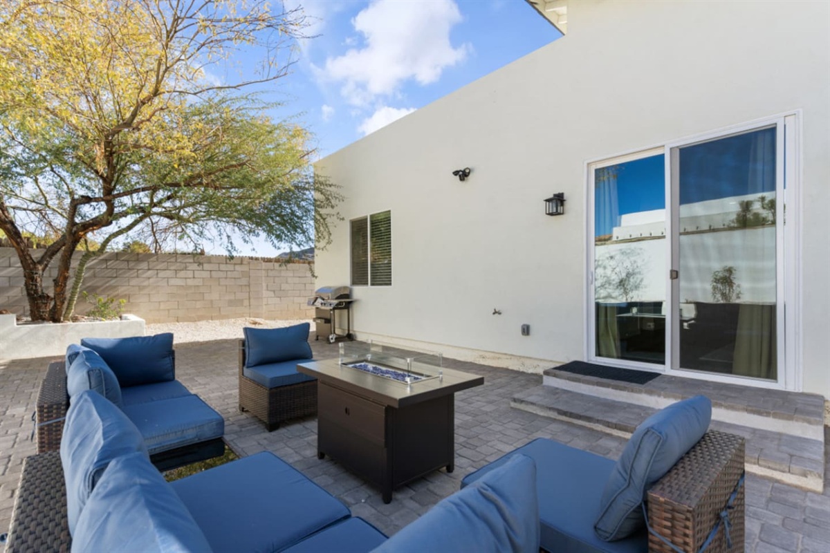 Outdoor living space with comfortable seating, grill, and a fire pit table for evening downtime.