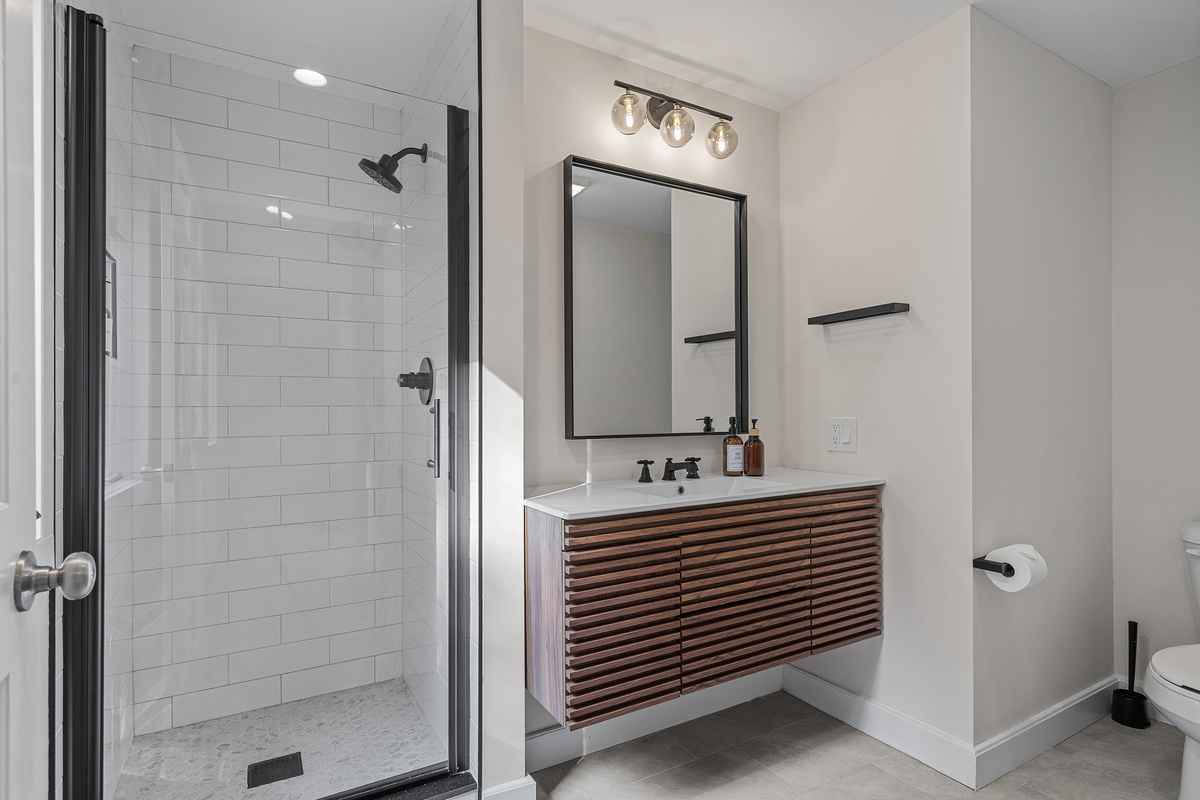 Modern bathroom with subway-tiled walk-in shower and floating wood vanity