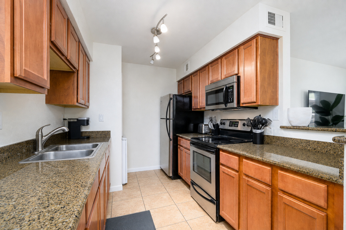 Kitchen setup with coffee maker, stove, microwave, refrigerator, and everyday cooking essentials.