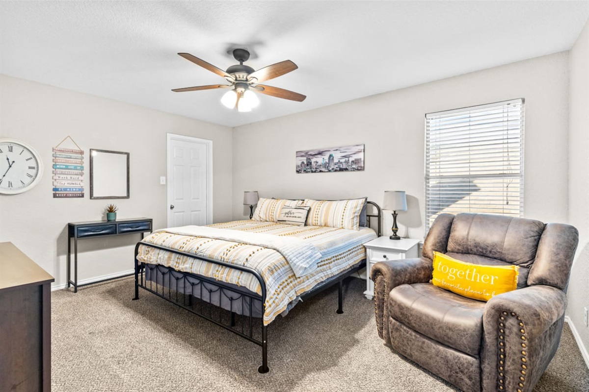 Cozy king bedroom retreat featuring a streaming-ready TV, soft linens, sofa chair, blackout blinds, and climate control for a peaceful and relaxing stay.