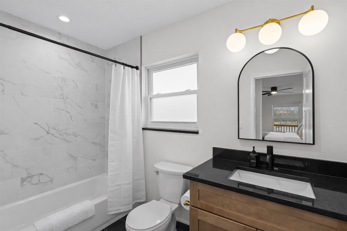 Clean, modern bathroom with a tiled tub/shower, sleek vanity, and bright lighting—designed for a refreshing, comfortable stay.