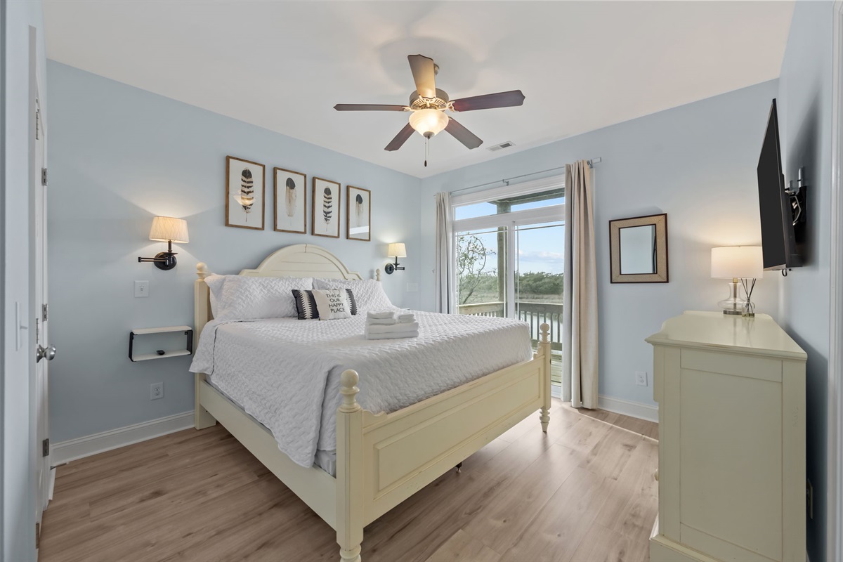 This serene master bedroom features crisp white linens, an en suite bath, with a private balcony overlooking the sound