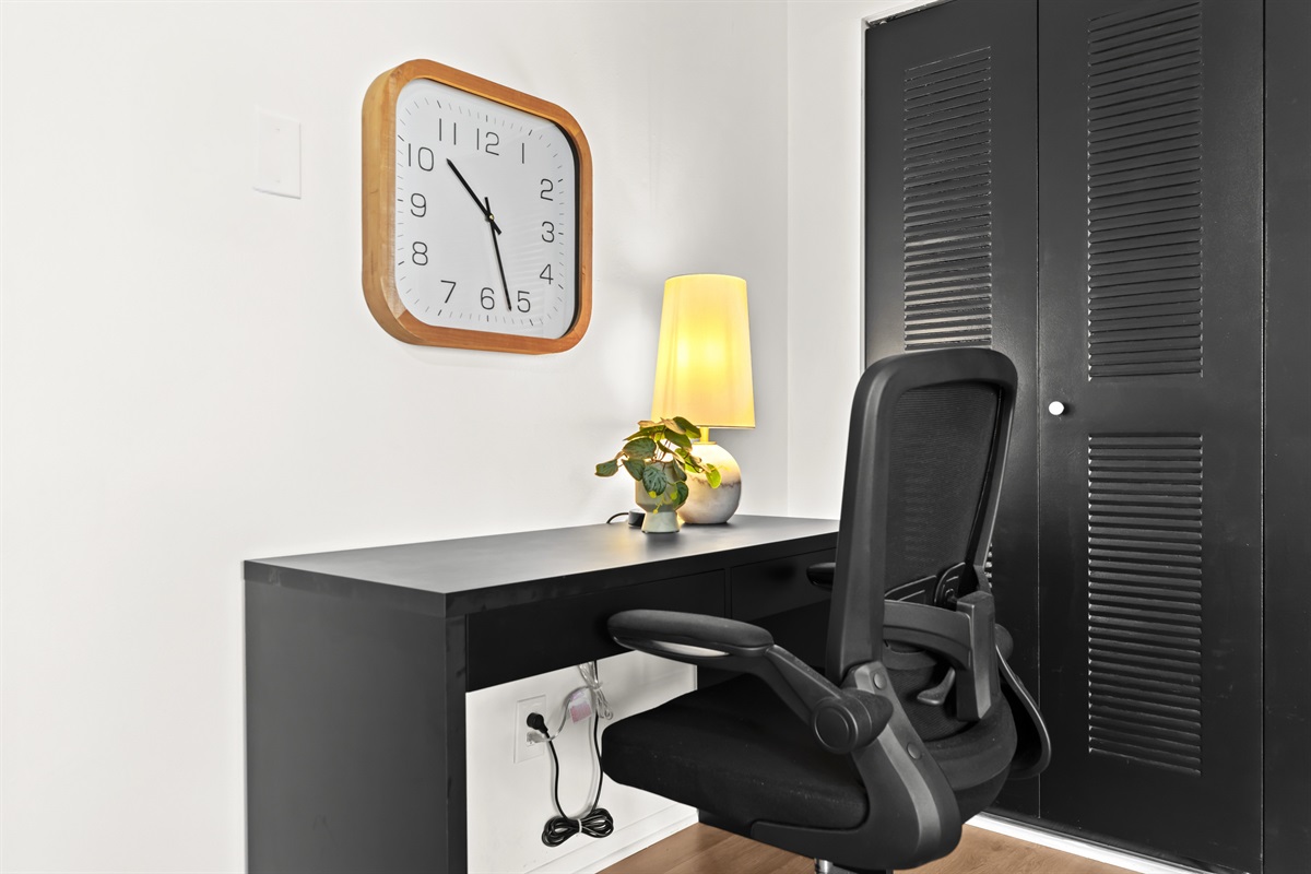 Well-lit workstation with desk, ergonomic chair, and charging access—ready for productivity.