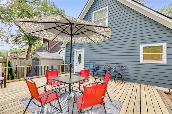 Spacious outdoor deck perfect for relaxing or entertaining, featuring comfortable seating, a large umbrella for shade, and a fresh open-air vibe.